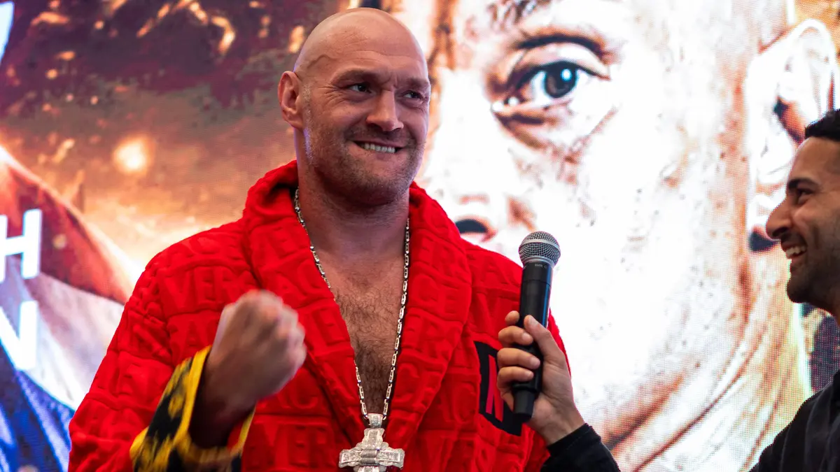 Tyson Fury in a red robe holding a microphone on stage